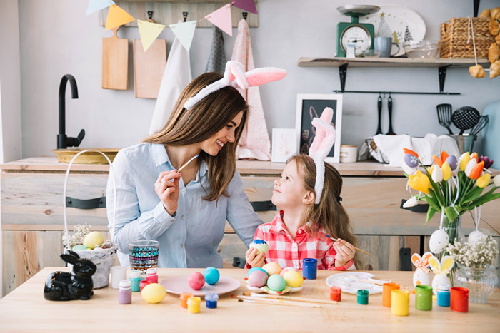 cute little girl painting eggs easter with mother n